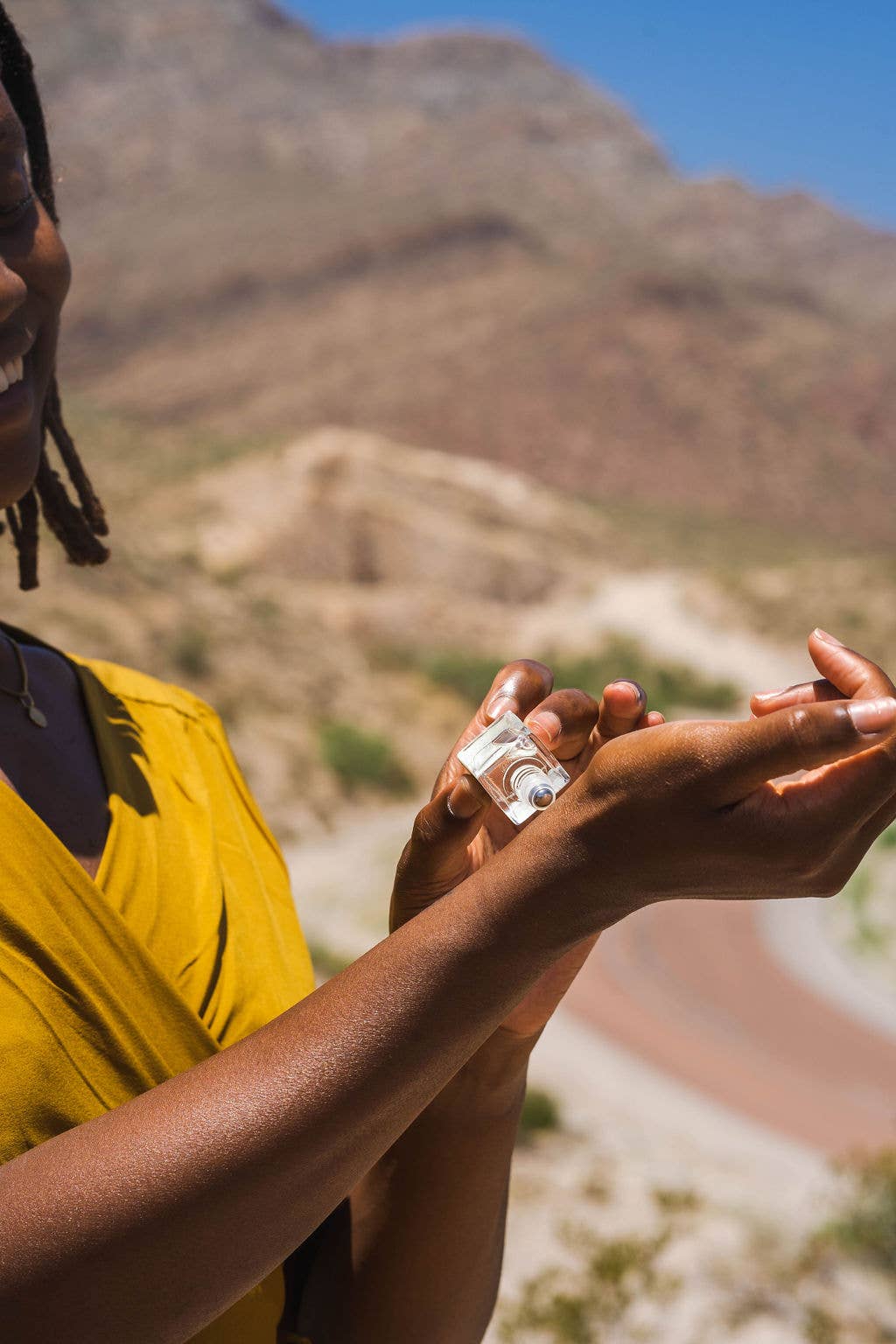 Person applying sunscreen on a mountainous background