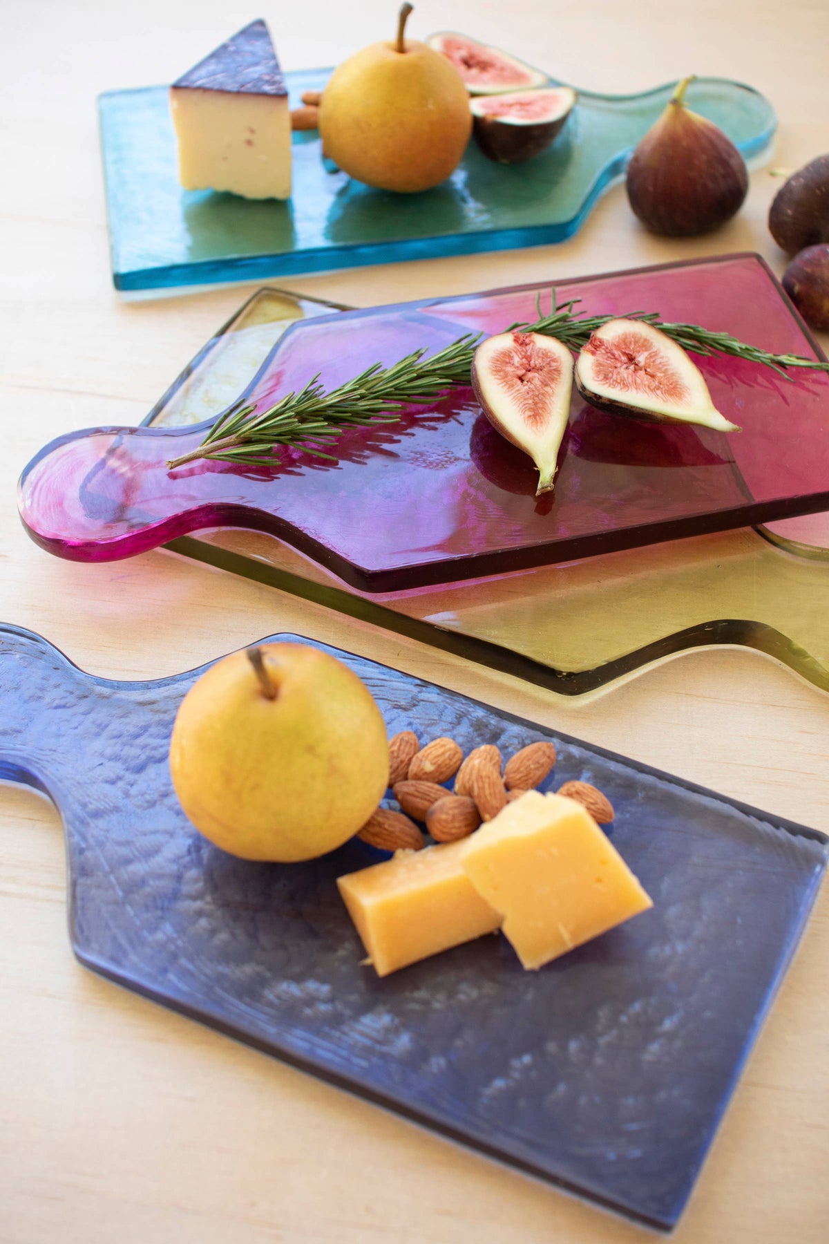 Assorted fruits and cheeses on colorful glass cutting boards.