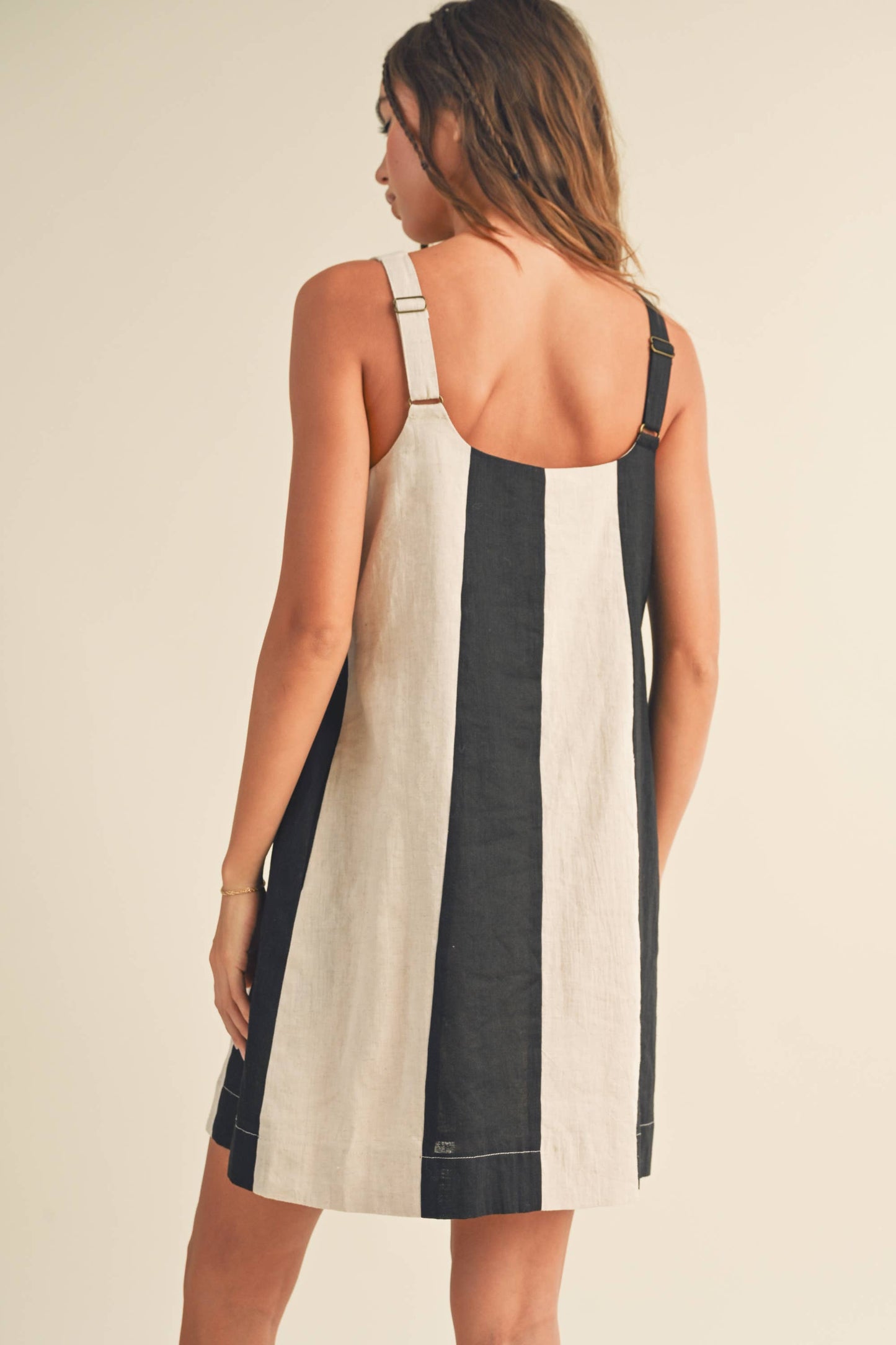Woman wearing a black and white striped dress on a beige background