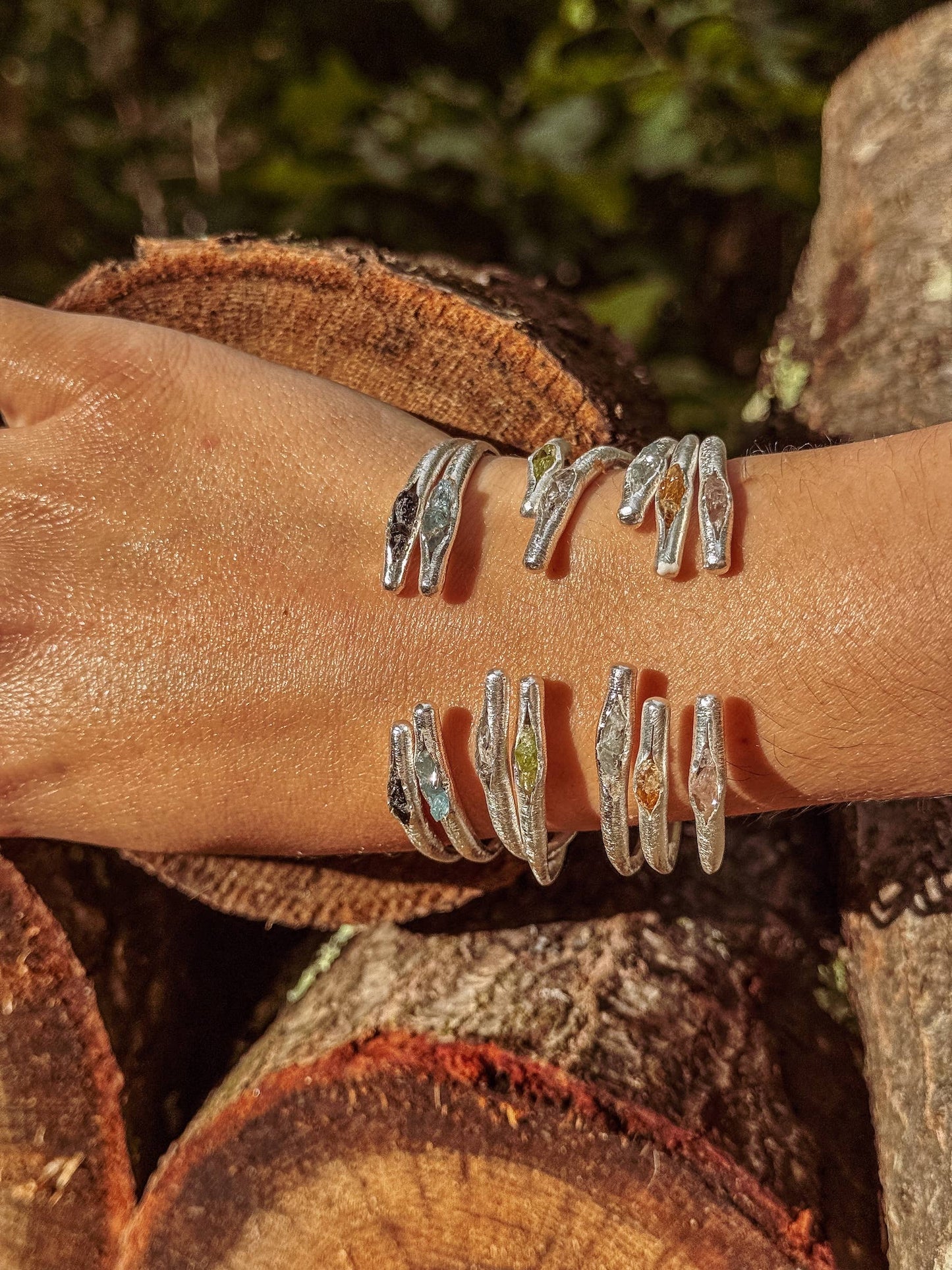 Silver rings on a person's wrist with a natural background of wood and foliage