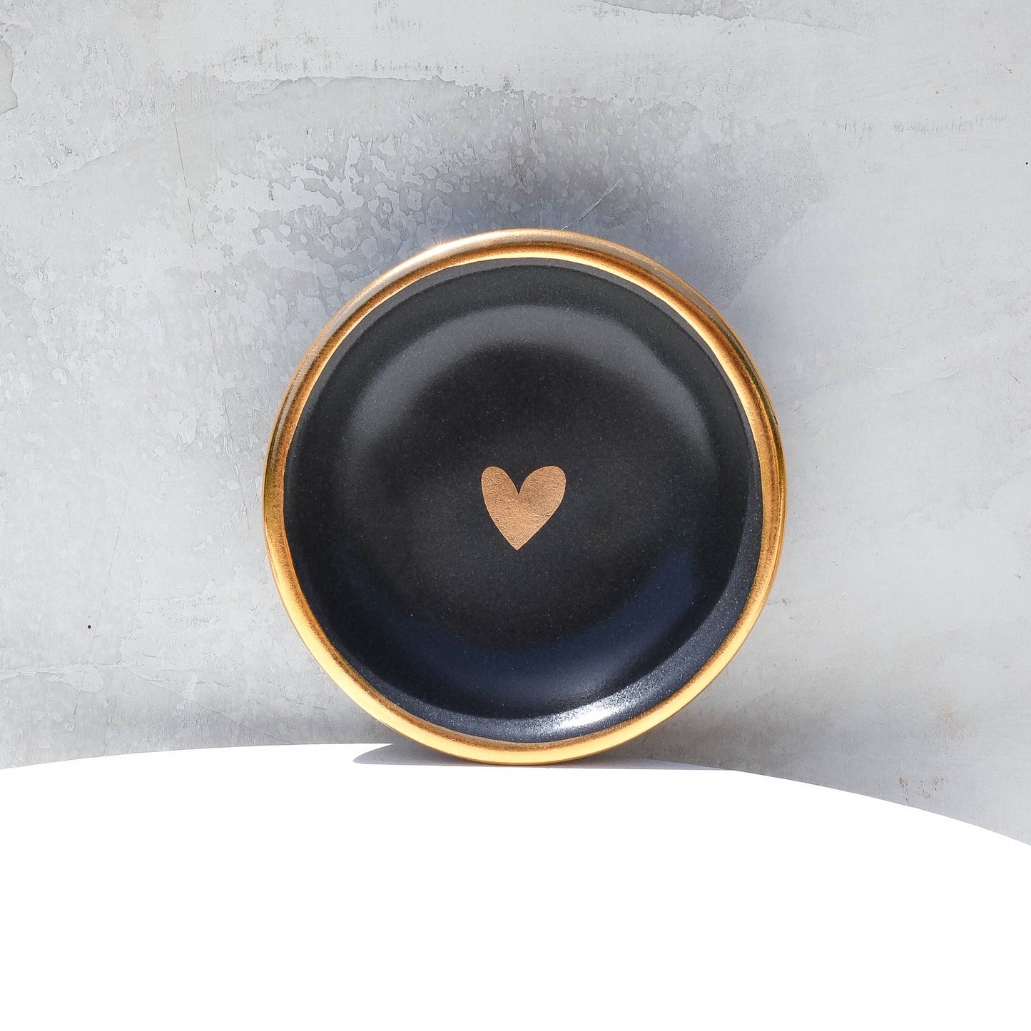Black dish with a gold heart on a gray background