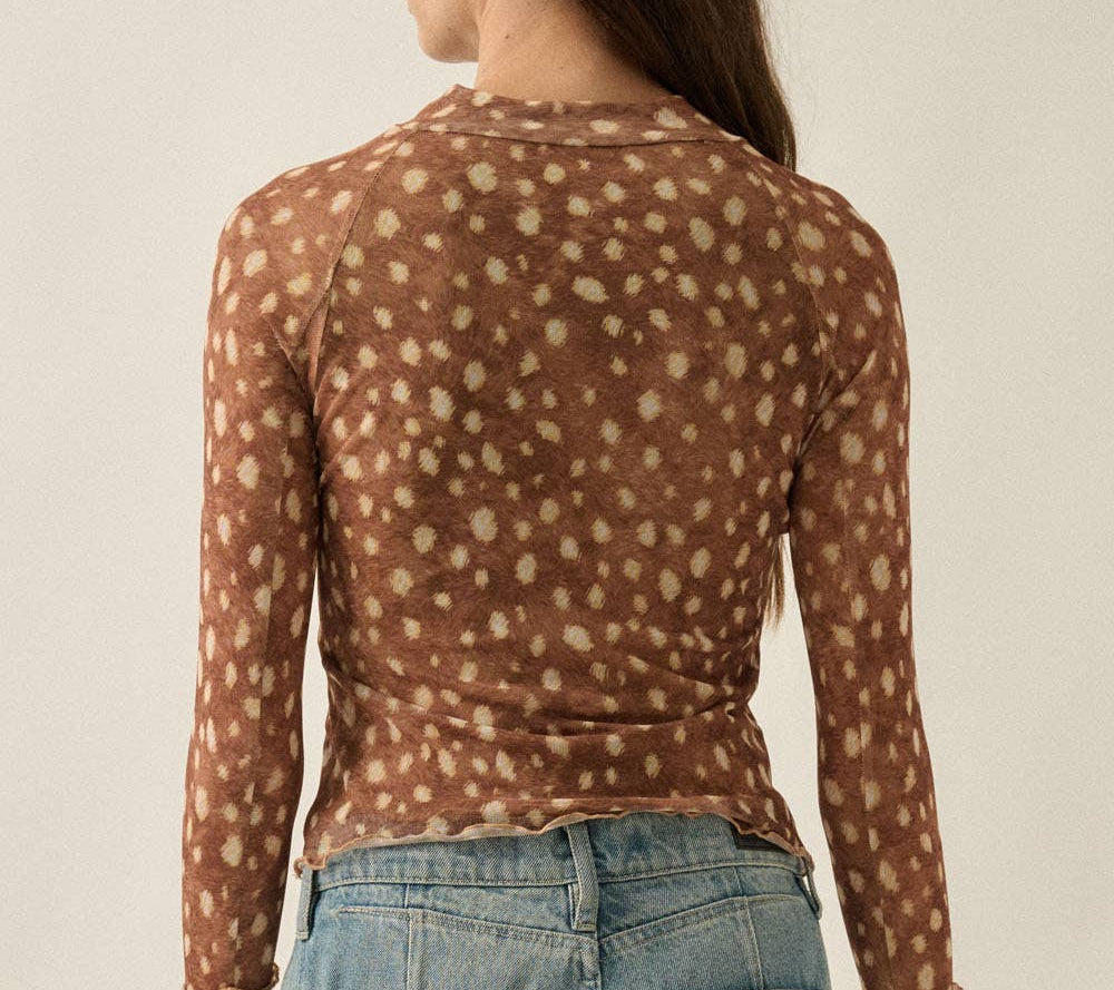 A woman shown from the back wearing a brown long-sleeve top with a beige dalmatian-style spot pattern, paired with light blue jeans, against a plain light beige background.