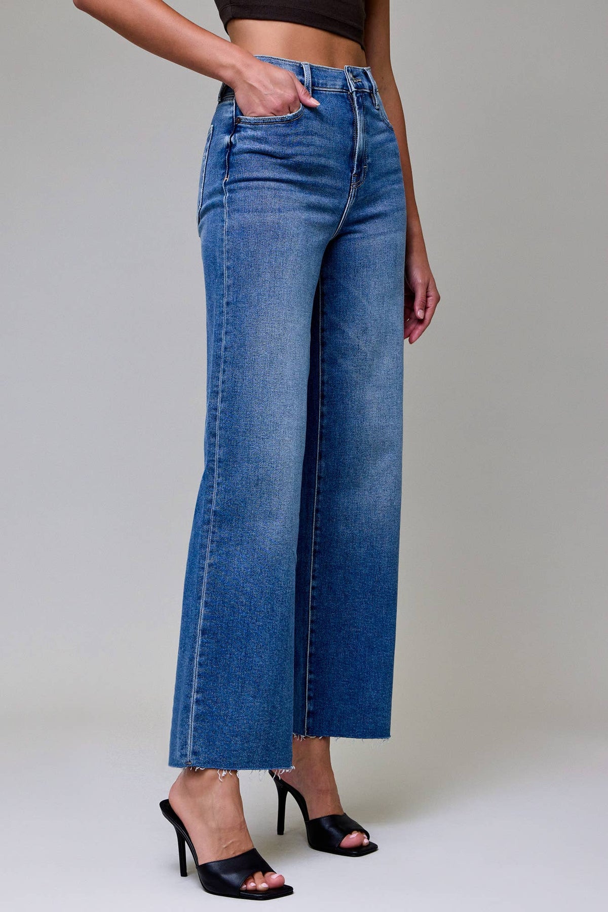 Person wearing blue jeans with a plain background