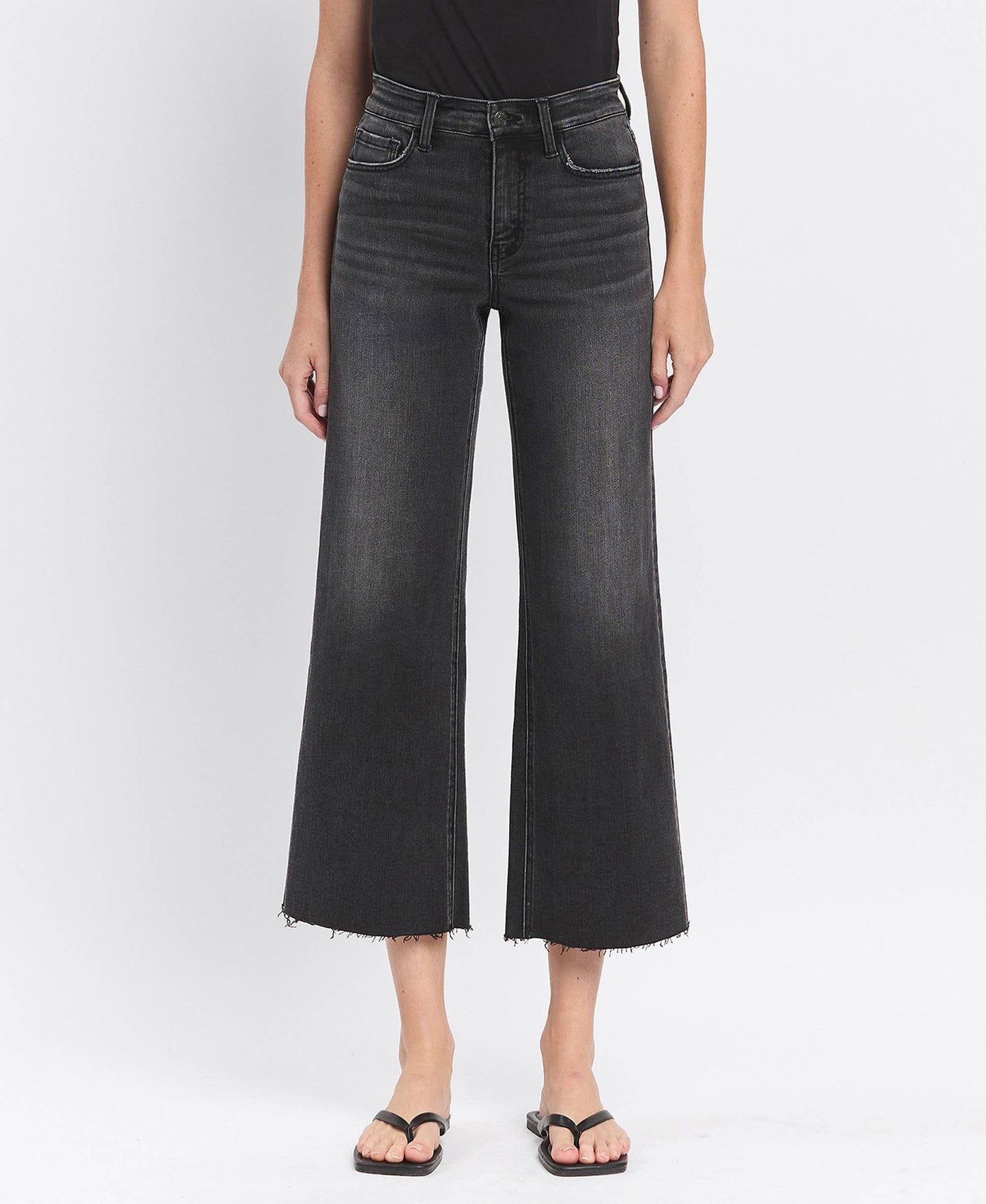 Person wearing black wide-leg jeans on a white background
