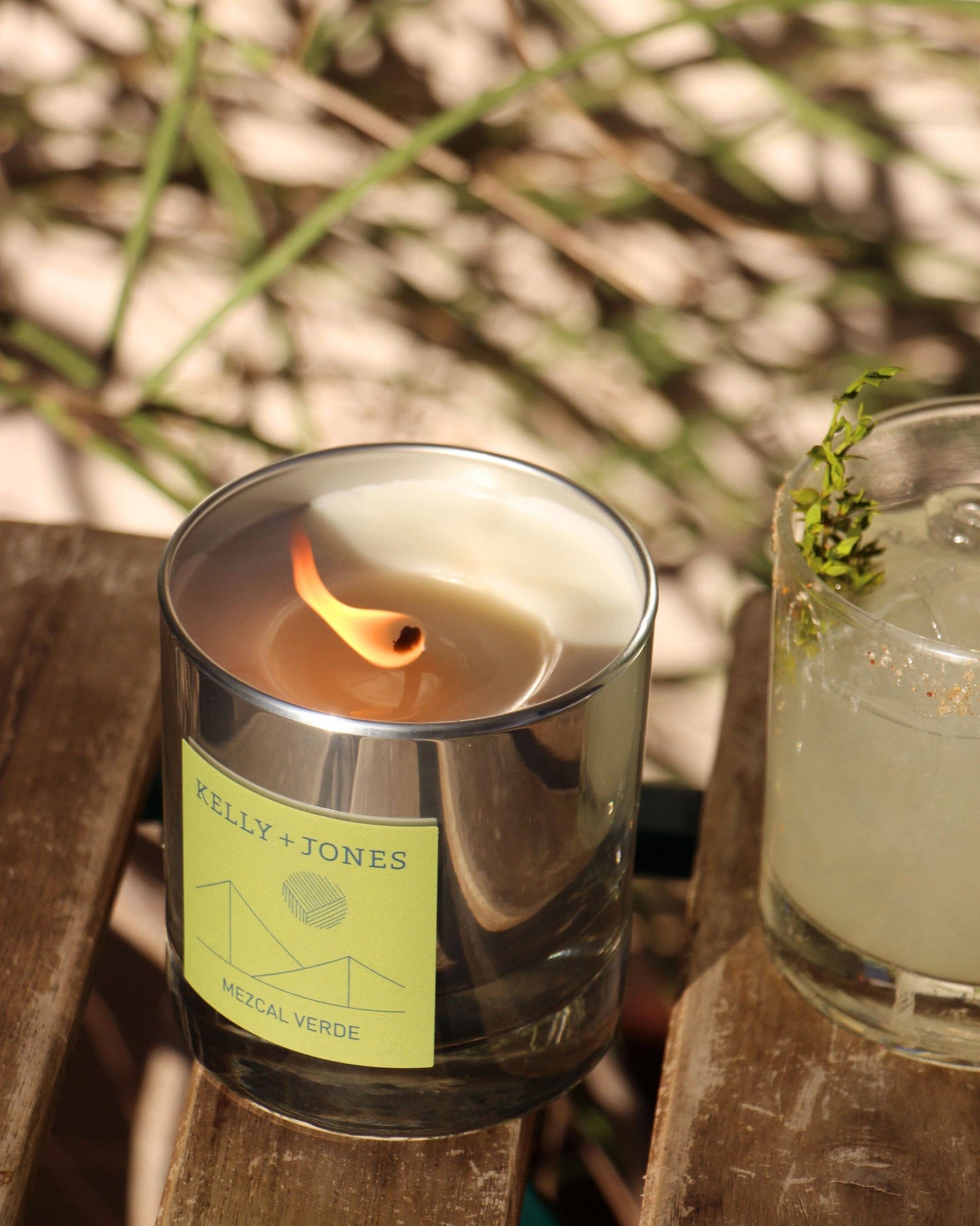 Candle with a 'Kelly & Jones' label on a wooden surface with blurred natural background