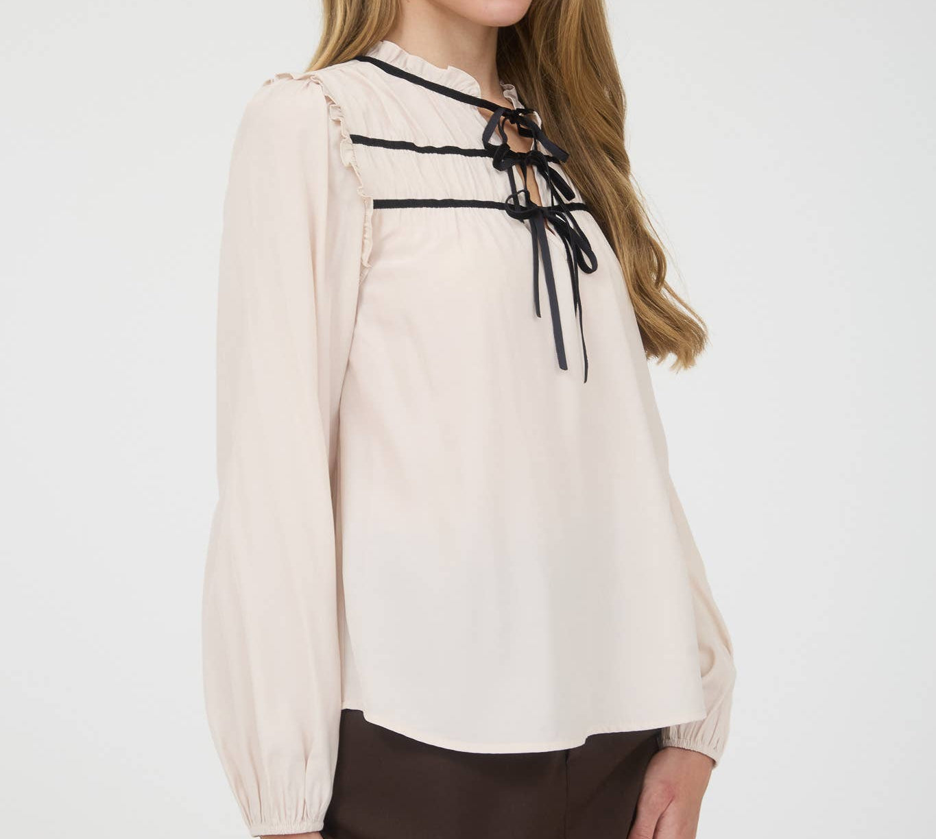 Beige blouse with black lace-up details on a white background