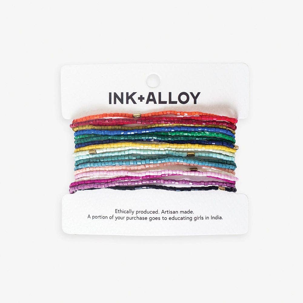 Set of colorful beaded hair ties on a 'INK+ALLOY' branded card with ethical message.