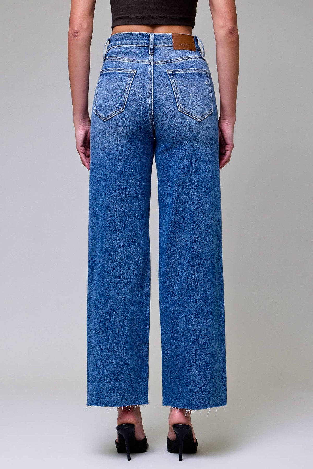 Person wearing blue jeans on a plain background