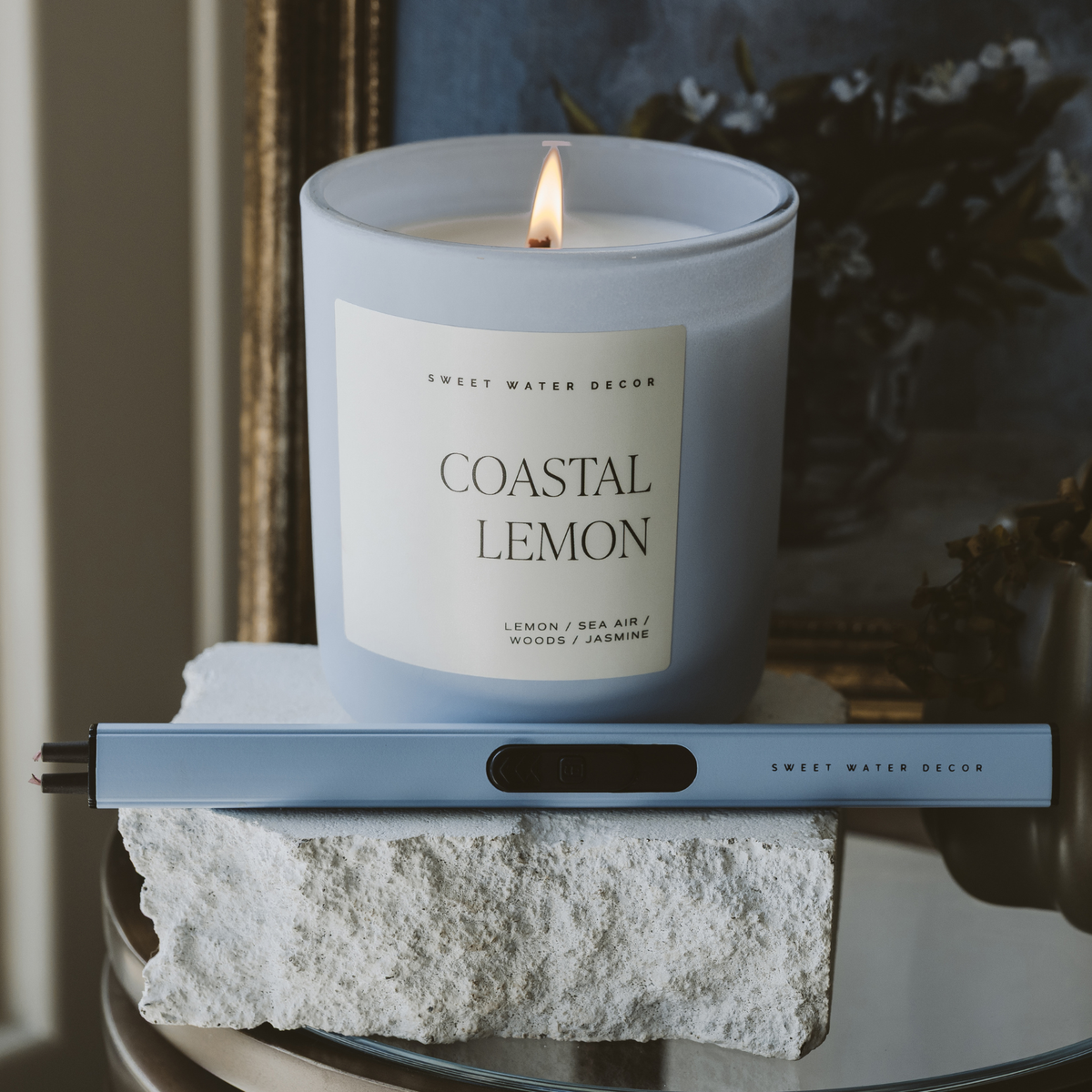Candle labeled 'Coastal Lemon' on a decorative stand with a blurred background