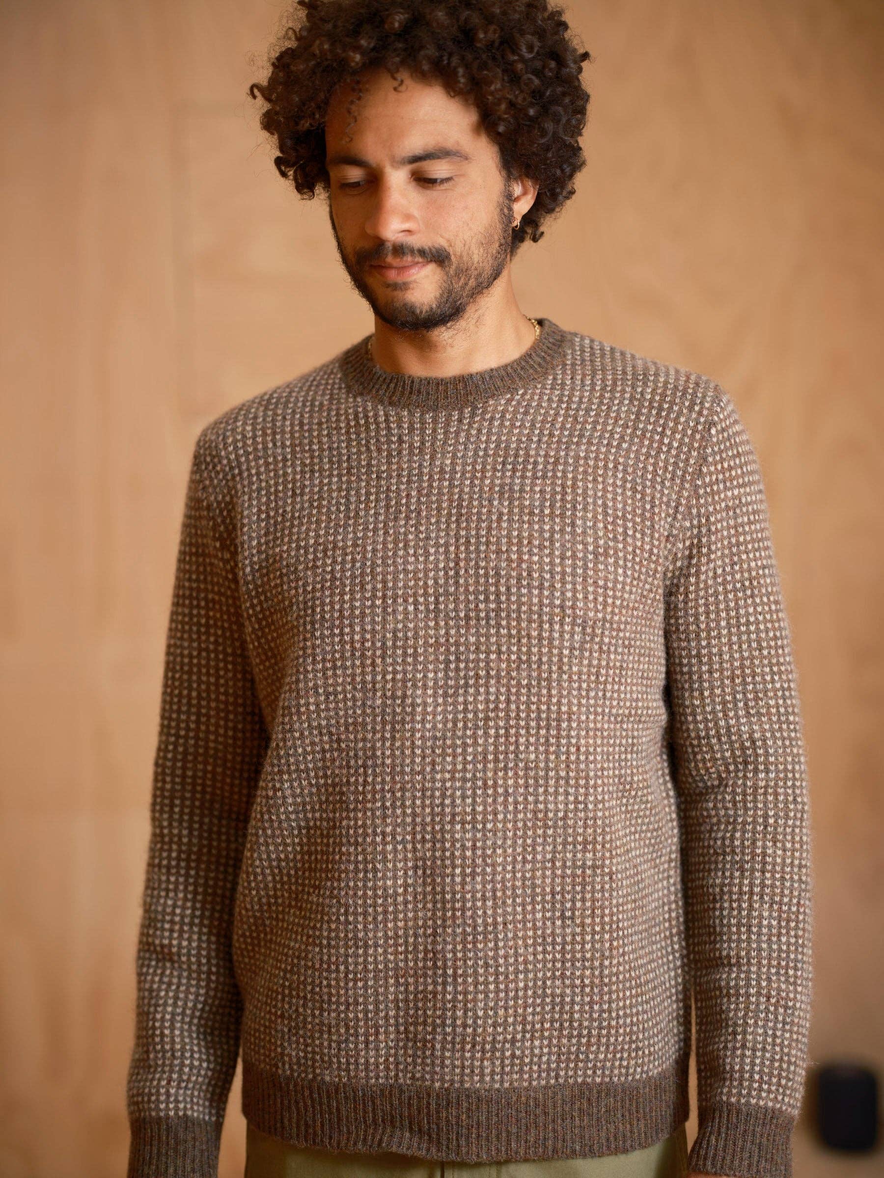 Man wearing a brown textured sweater against a beige background