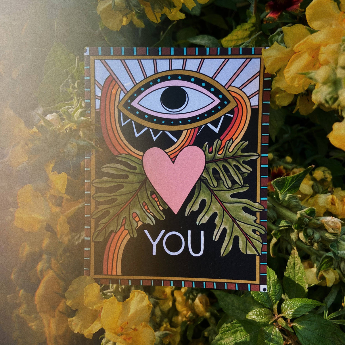 Card with eye and heart design surrounded by flowers