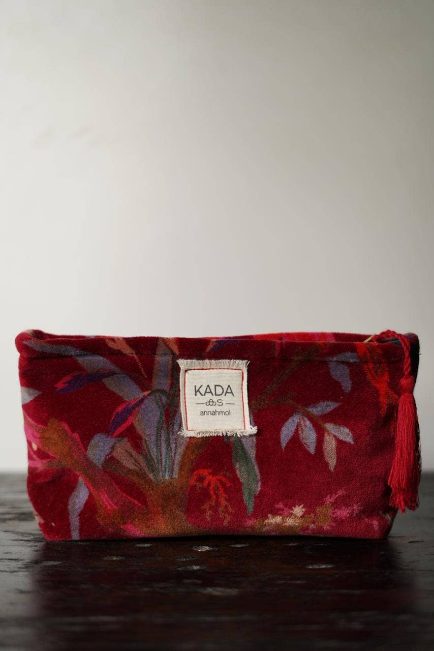 Red floral pouch with 'KADA' label on a dark surface