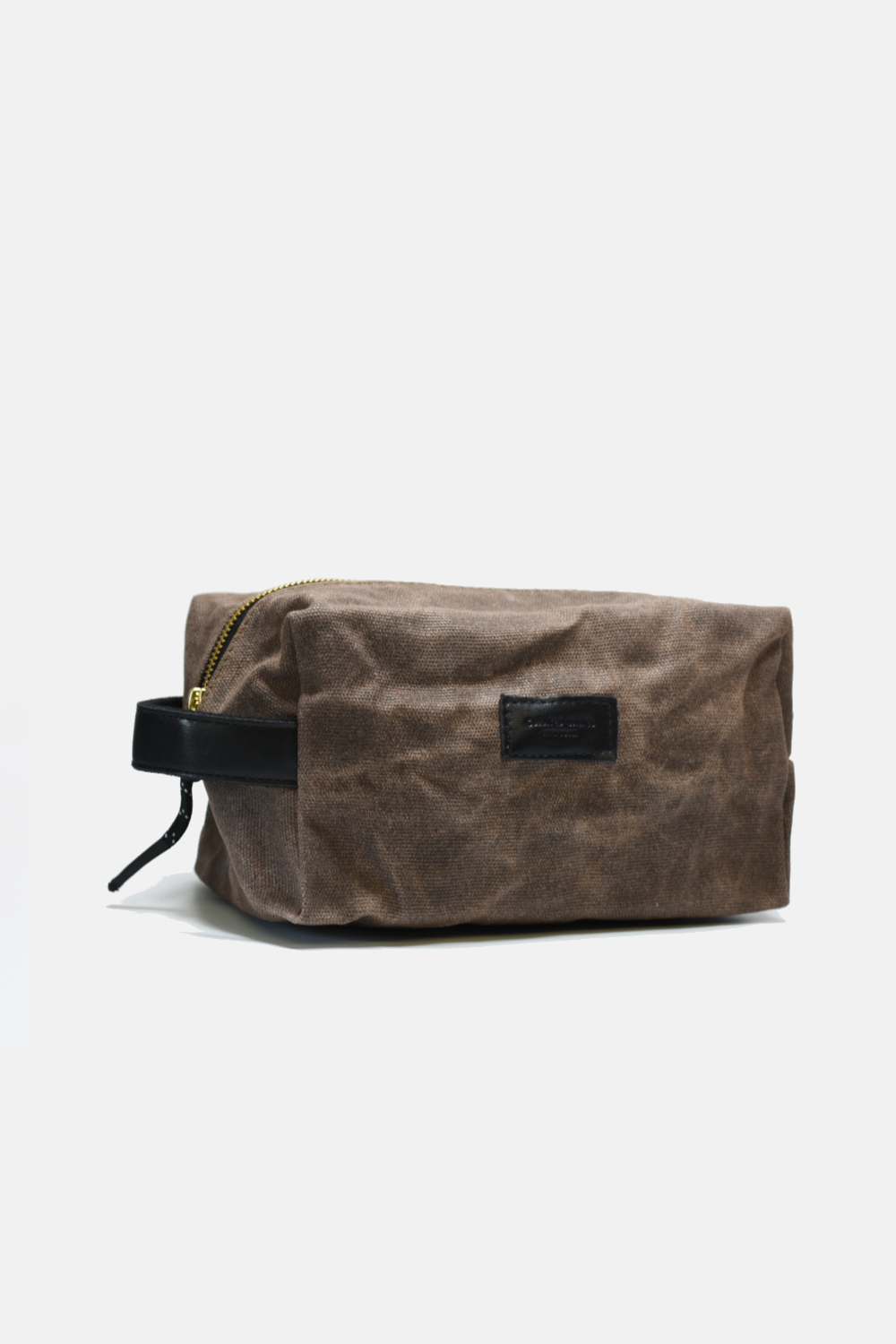 Brown waxed canvas dopp kit with black zipper and strap on a white background