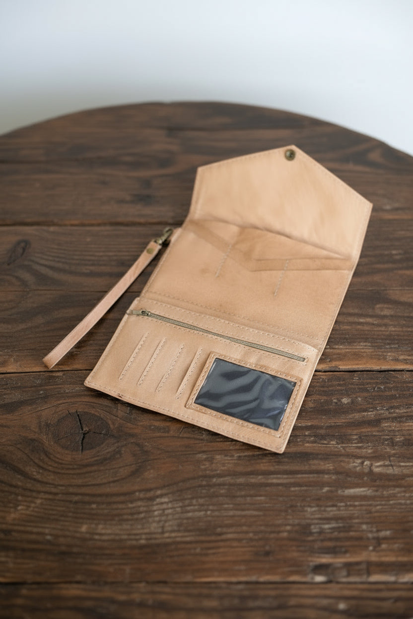 Beige leather wallet with a strap on a wooden surface