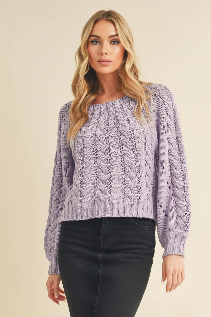 Woman wearing a purple cable knit sweater and black cap on a beige background