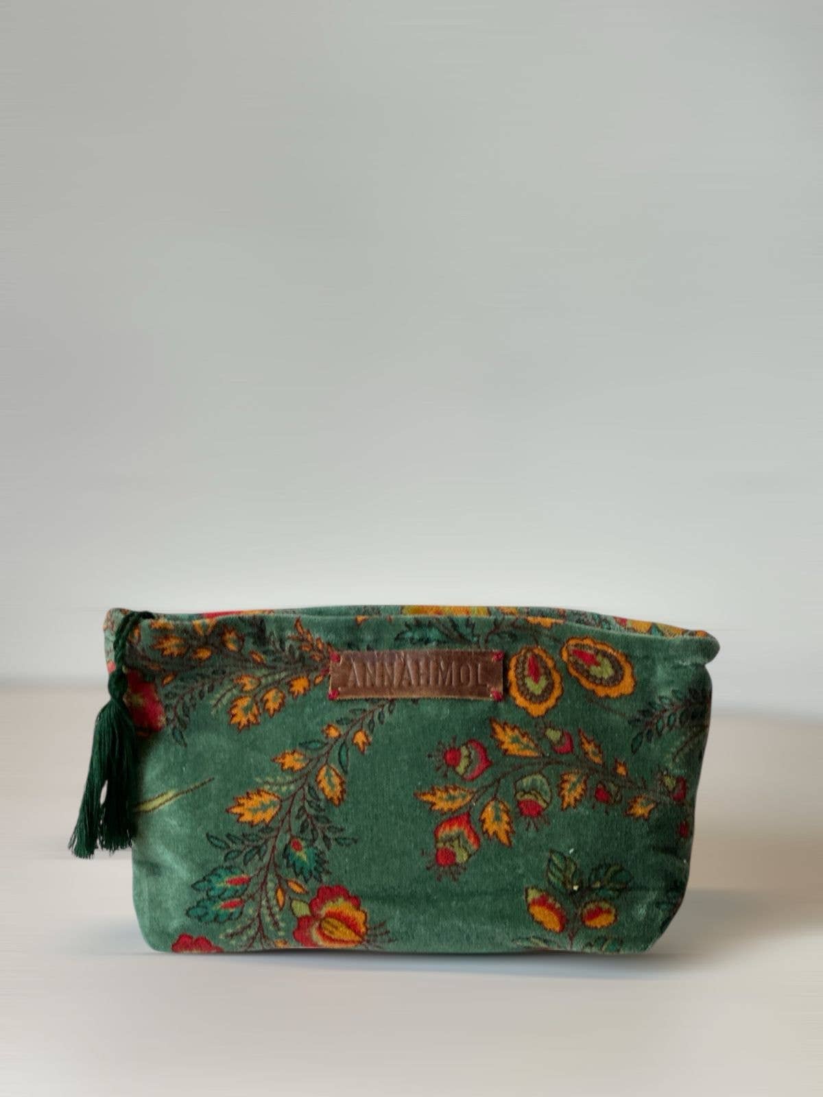 Green floral-patterned pouch with tassels on a white background