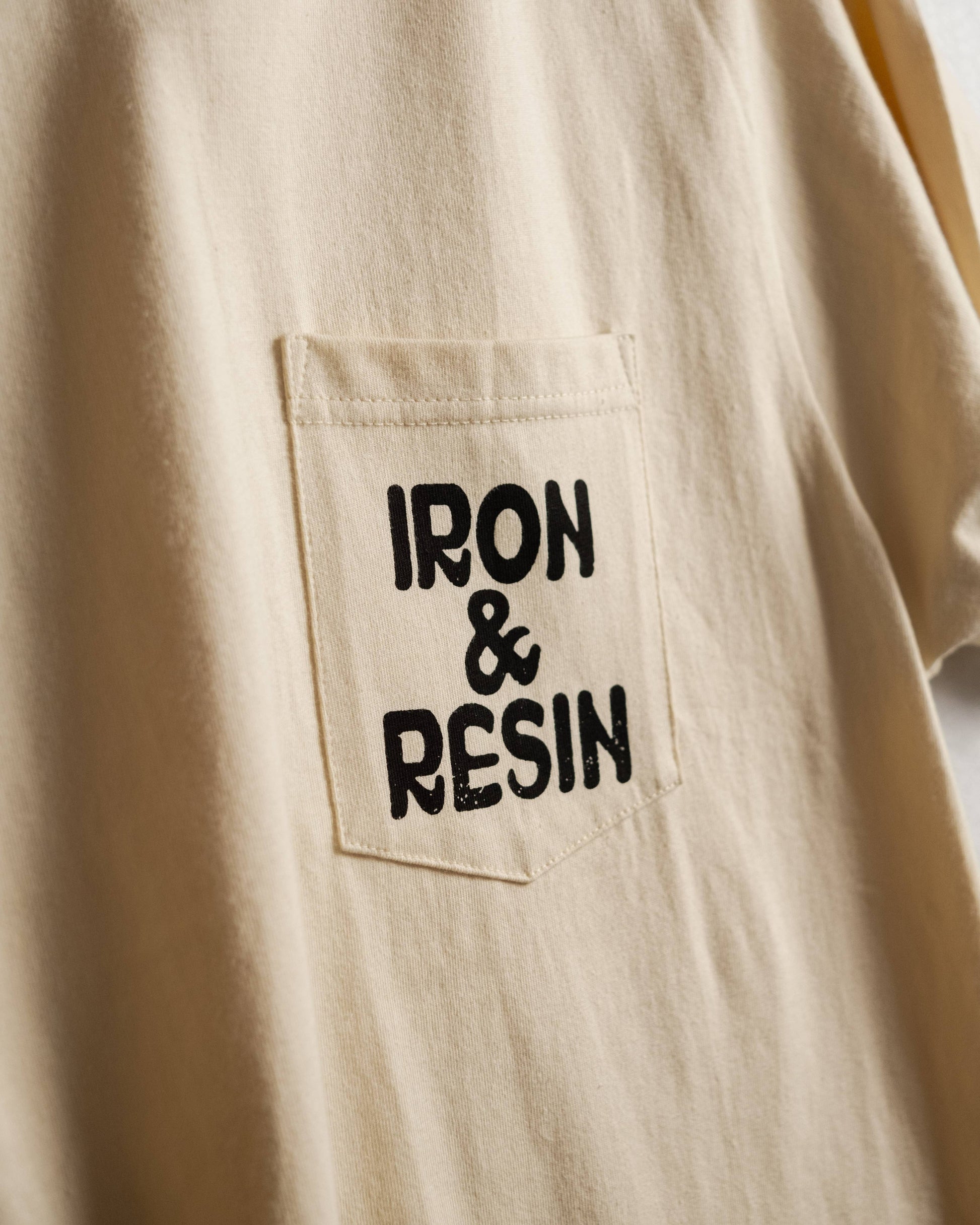 Beige shirt with 'IRON & RESIN' logo on a pocket