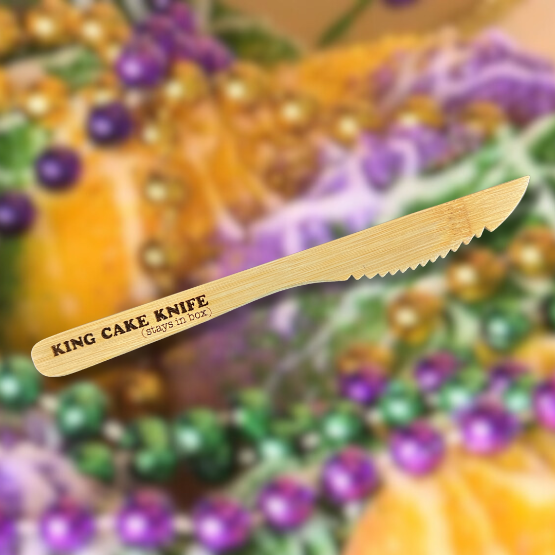King cake knife with text on a blurred background of colorful beads and pumpkins