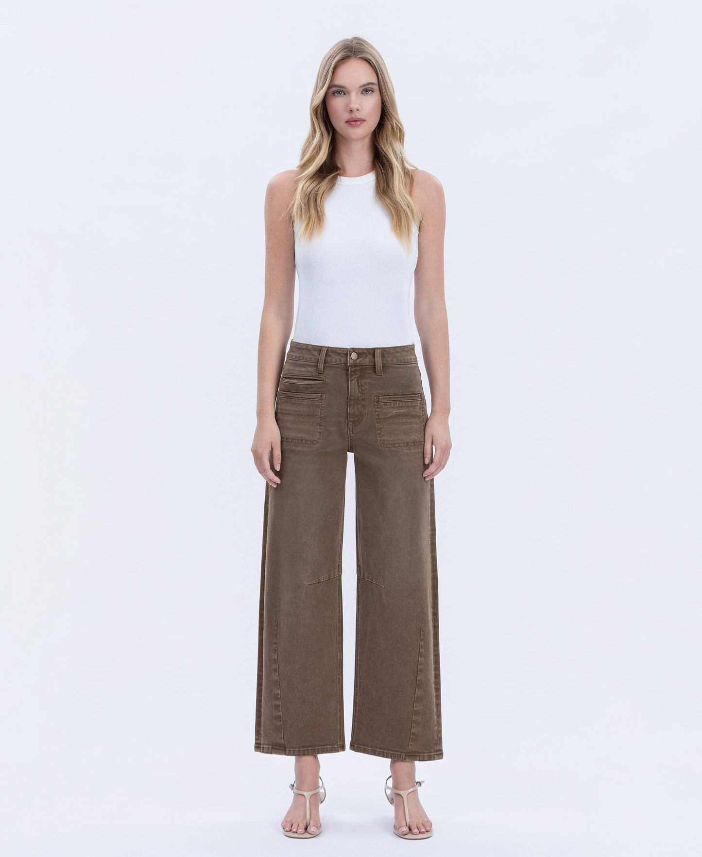 Woman wearing brown wide-leg pants and a white top on a white background