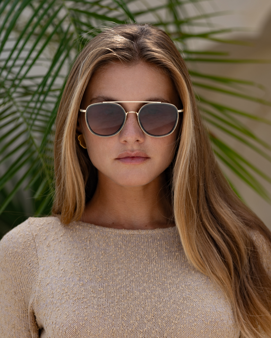 Woman wearing sunglasses with a blurred green leafy background
