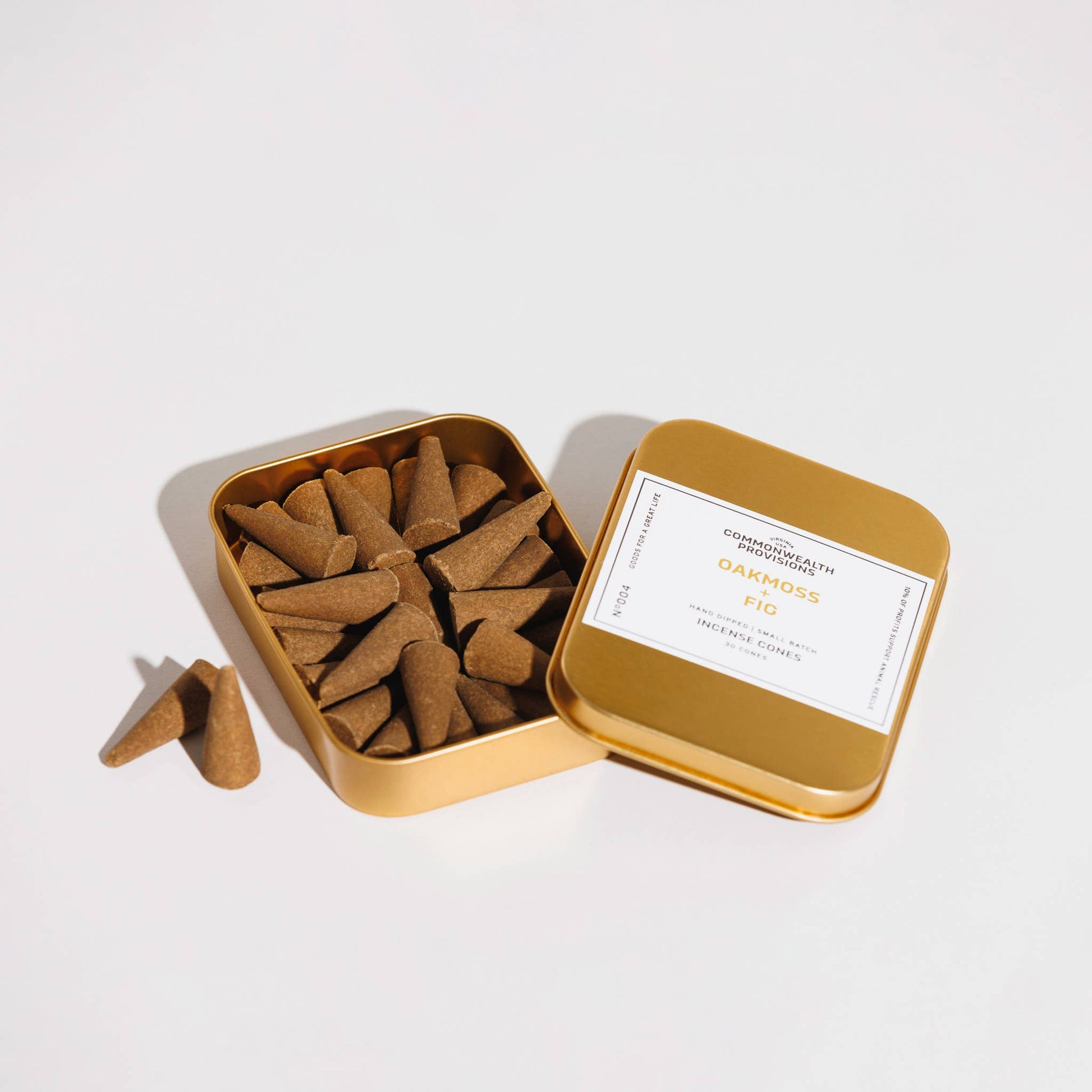 Open gold tin filled with incense cones on a white background