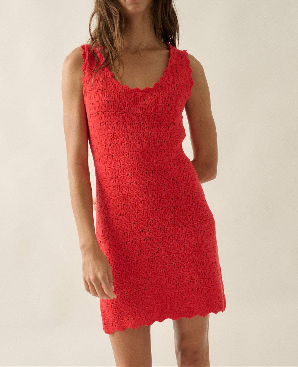 Woman wearing a red crochet dress against a plain background