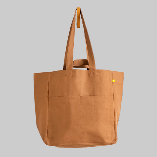A large brown canvas tote bag with dual shoulder straps, a top carry handle, and two front pockets, shown against a plain white background.