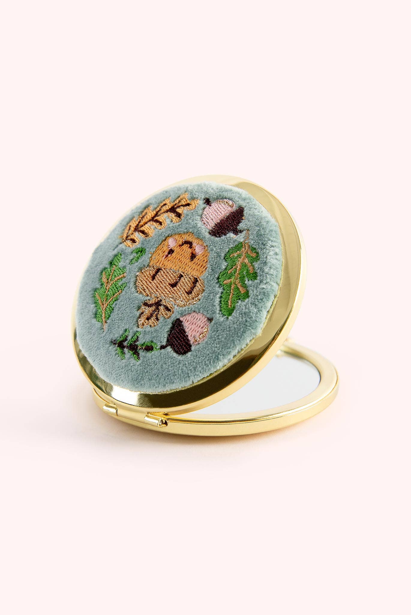 Compact mirror with embroidered design of a bear and nature elements on a light blue background