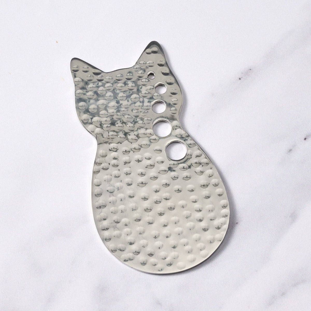 Metallic cat-shaped object on a white marble surface