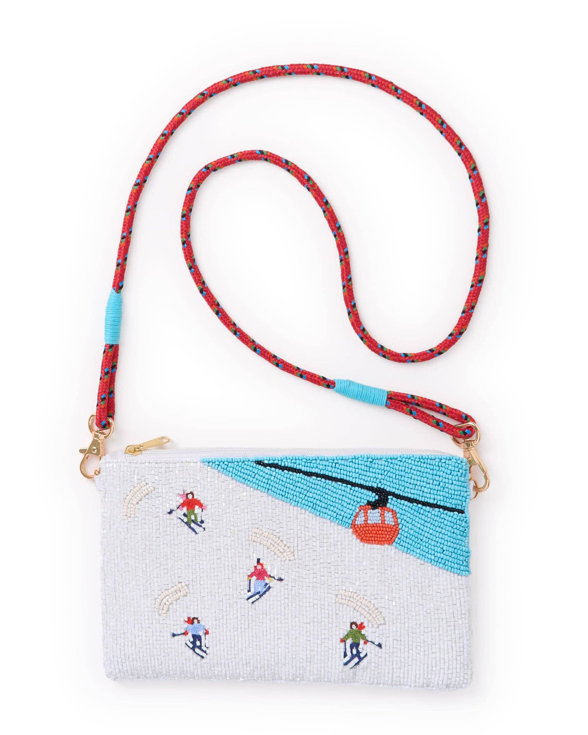 A rectangular crossbody clutch bag with a white and light blue beaded ski-themed design, featuring embroidered skiers and a red gondola. It has a red braided shoulder strap with blue accents and gold-tone hardware, shown on a plain white background.