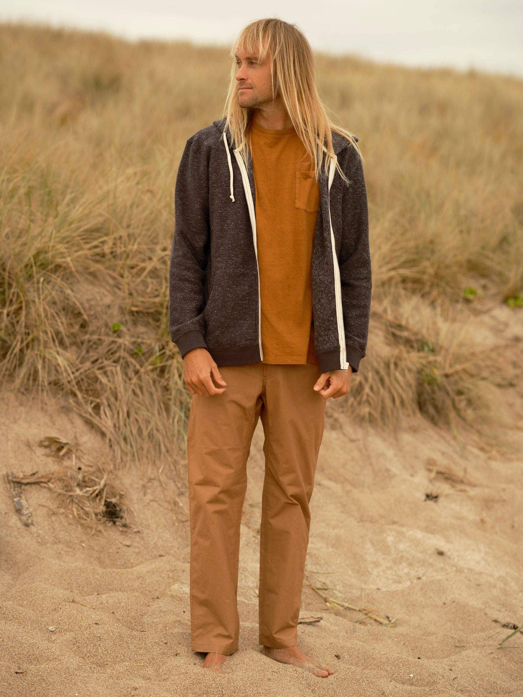 Man standing on a sandy path with grasses in the background
