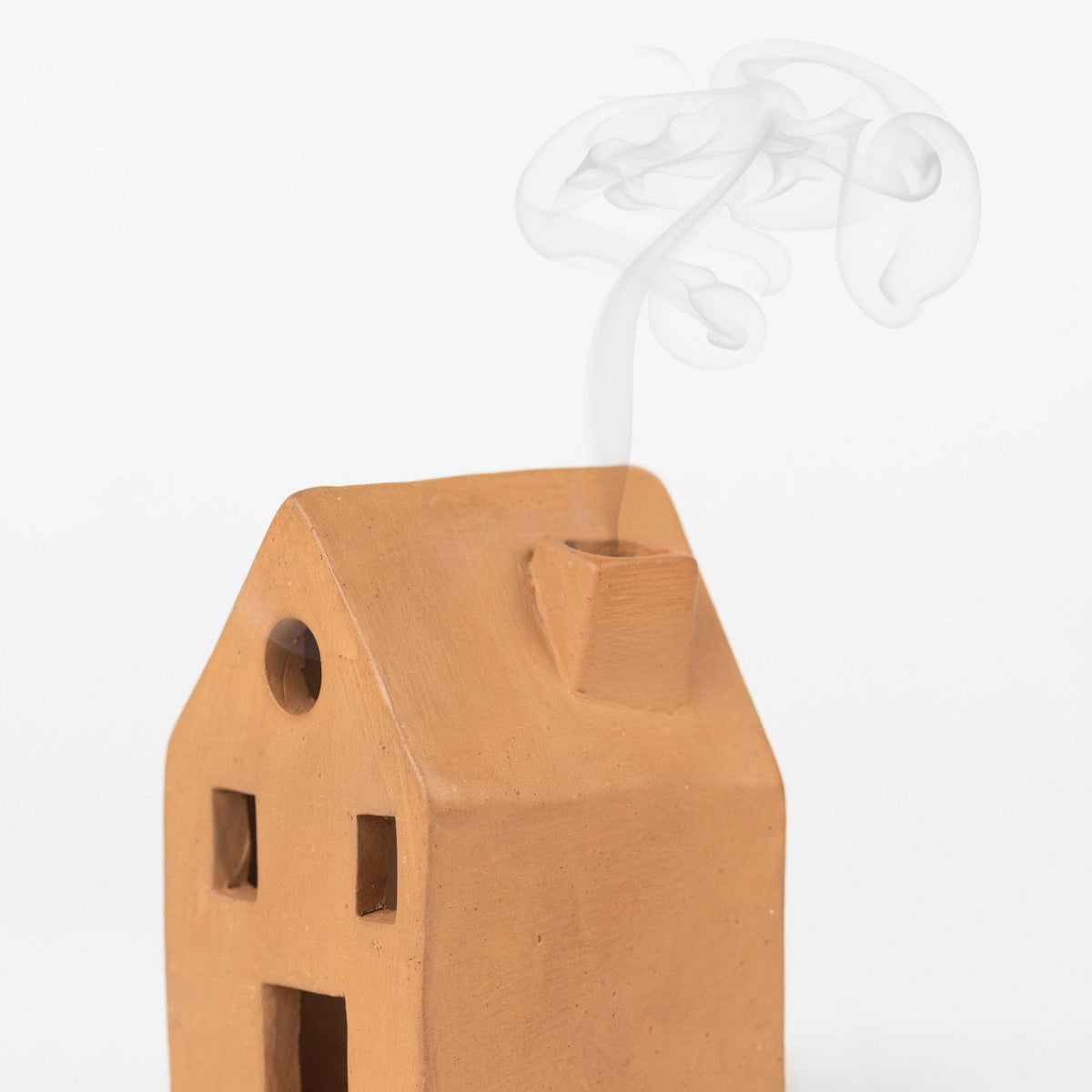 Wooden house-shaped candle holder with a small flame on a white background
