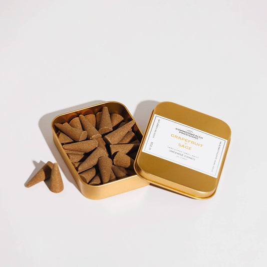 Open gold tin filled with incense cones on a white background