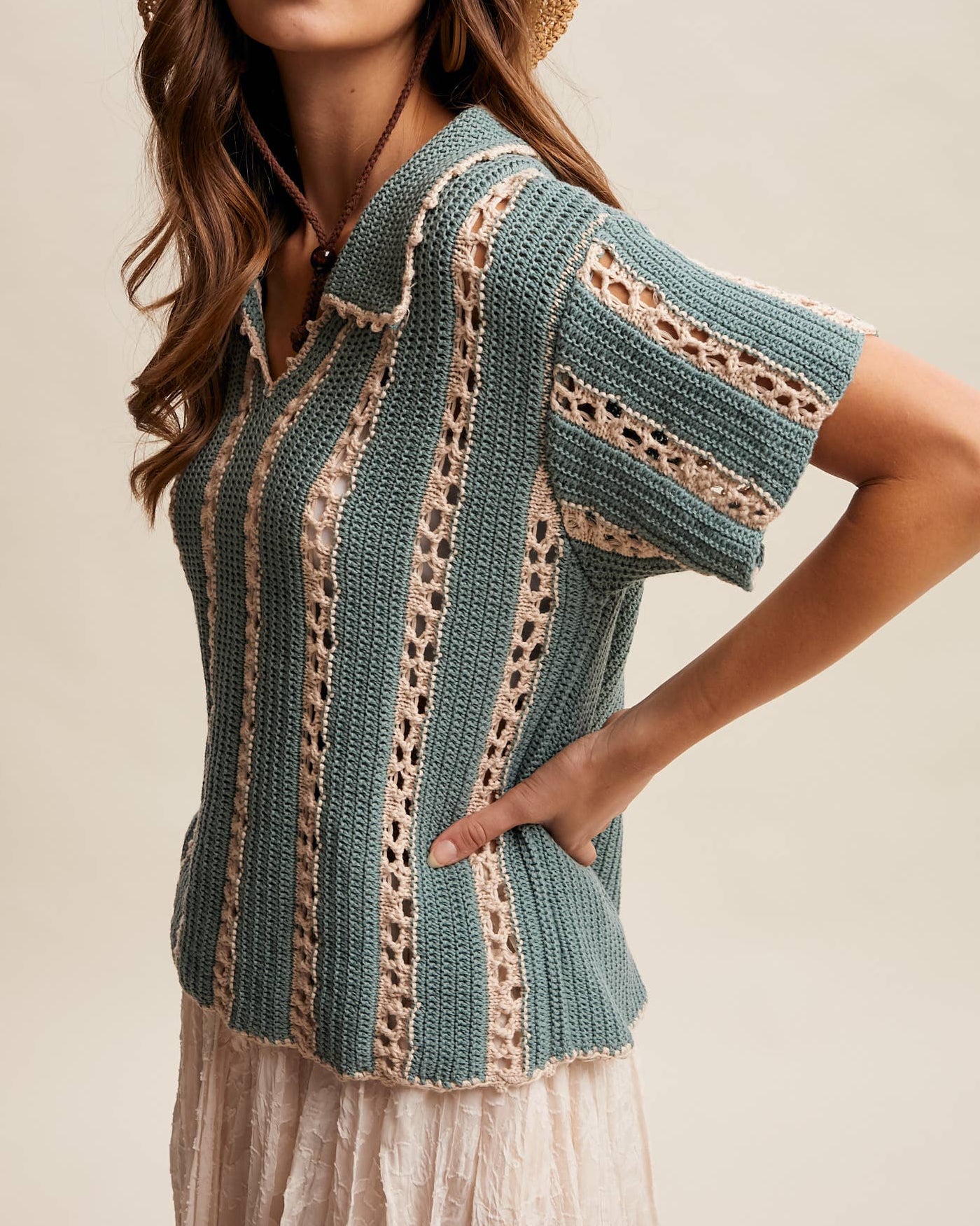 Woman wearing a knitted top and straw hat on a beige background