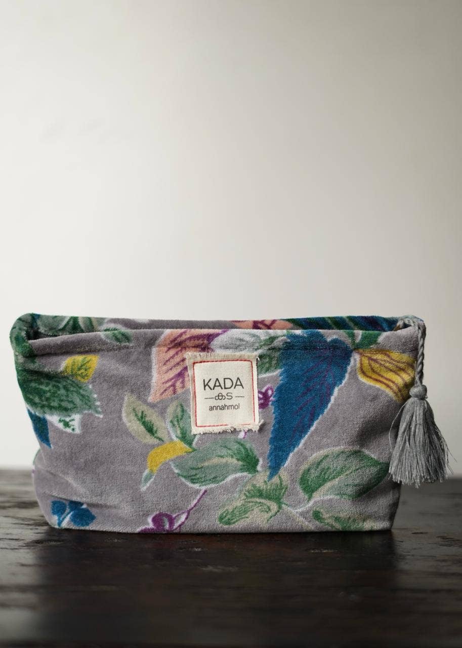 Floral-patterned pouch with a tassel on a wooden surface, featuring the brand 'KADA'.