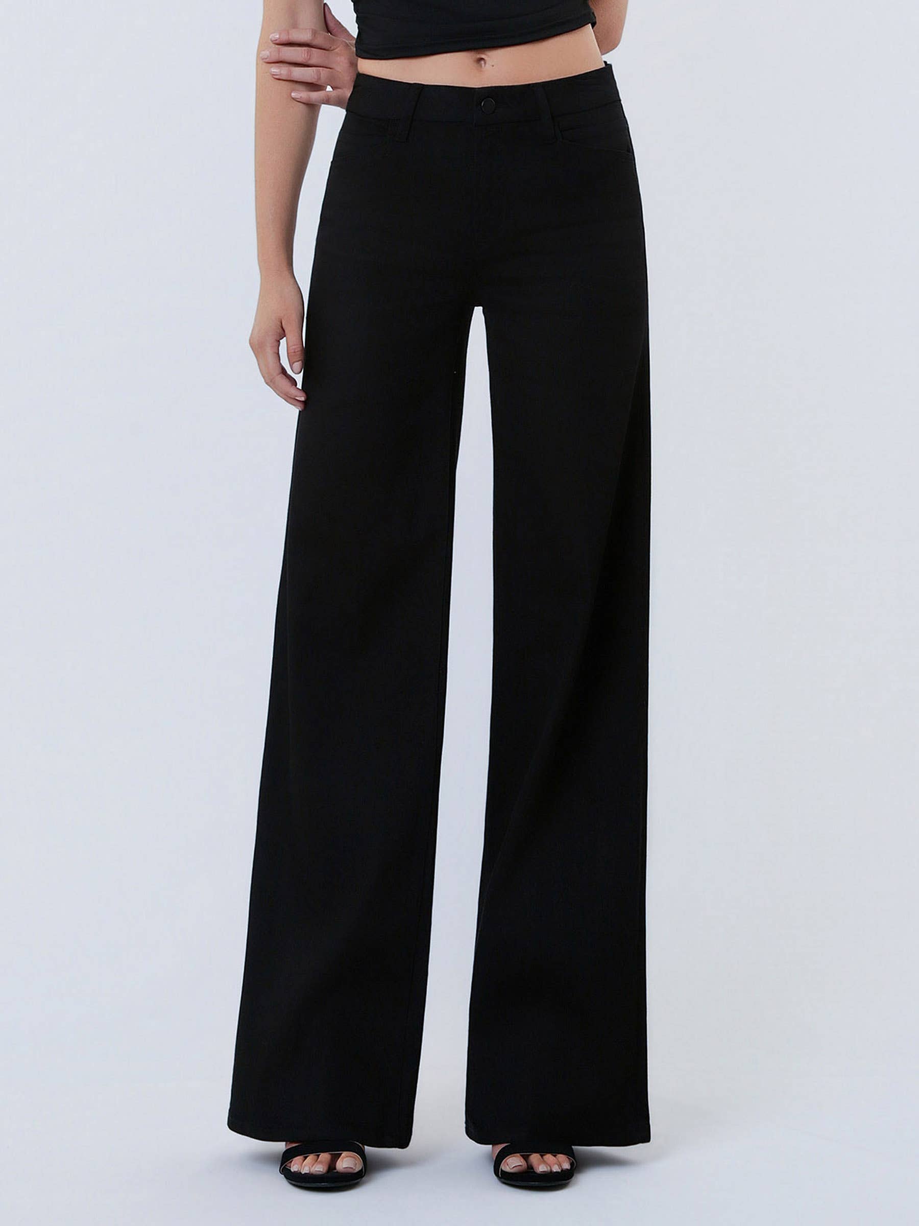 Person wearing black wide-leg pants on a light gray background