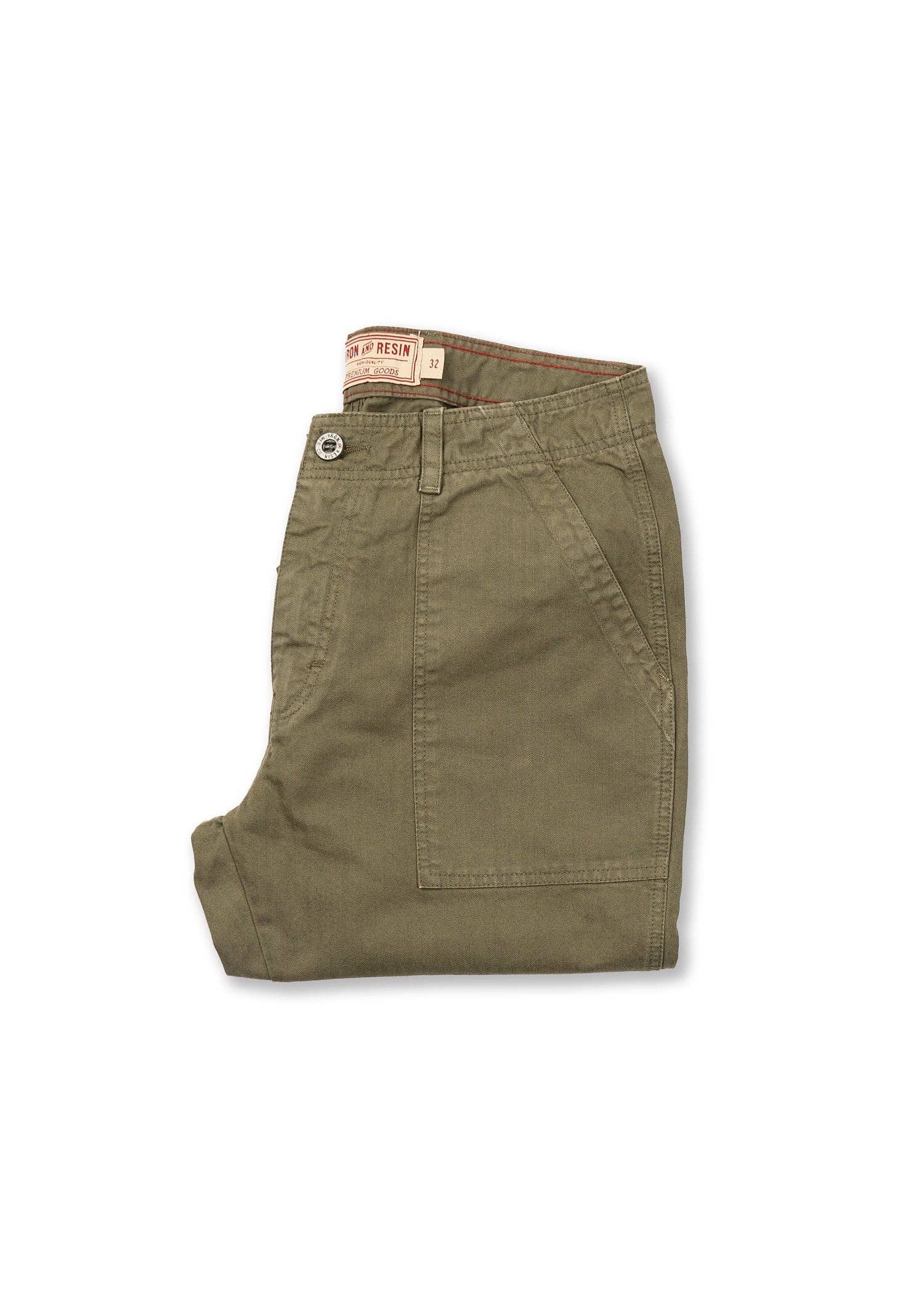 Folded green pants with a brand label on a white background