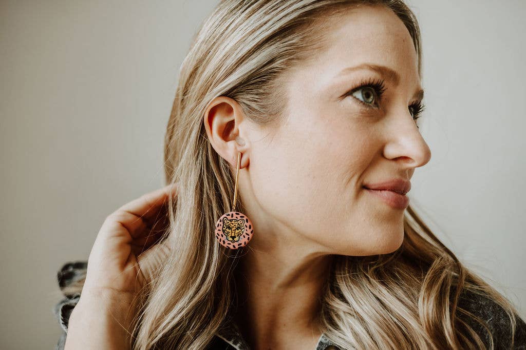 Woman wearing pink floral earrings with a neutral background