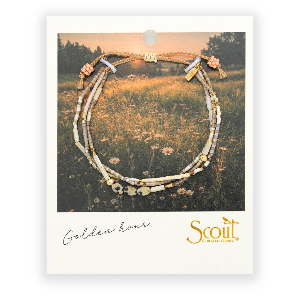 Necklace on a card with 'Scout' branding and 'Golden Hour' text, set against a nature-themed background.