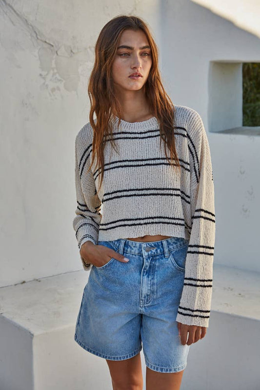 Cropped ribbed crew neck sweater with double-striped pattern, relaxed fit, and dropped shoulders in soft polyester fabric.