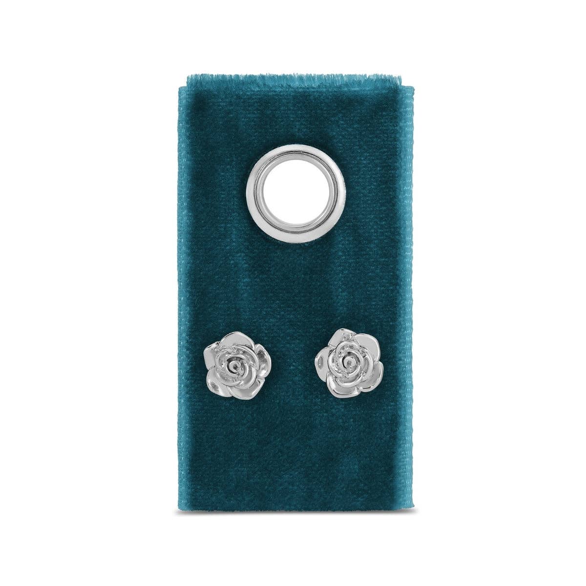 Silver rose-shaped earrings on a blue velvet stand against a white background