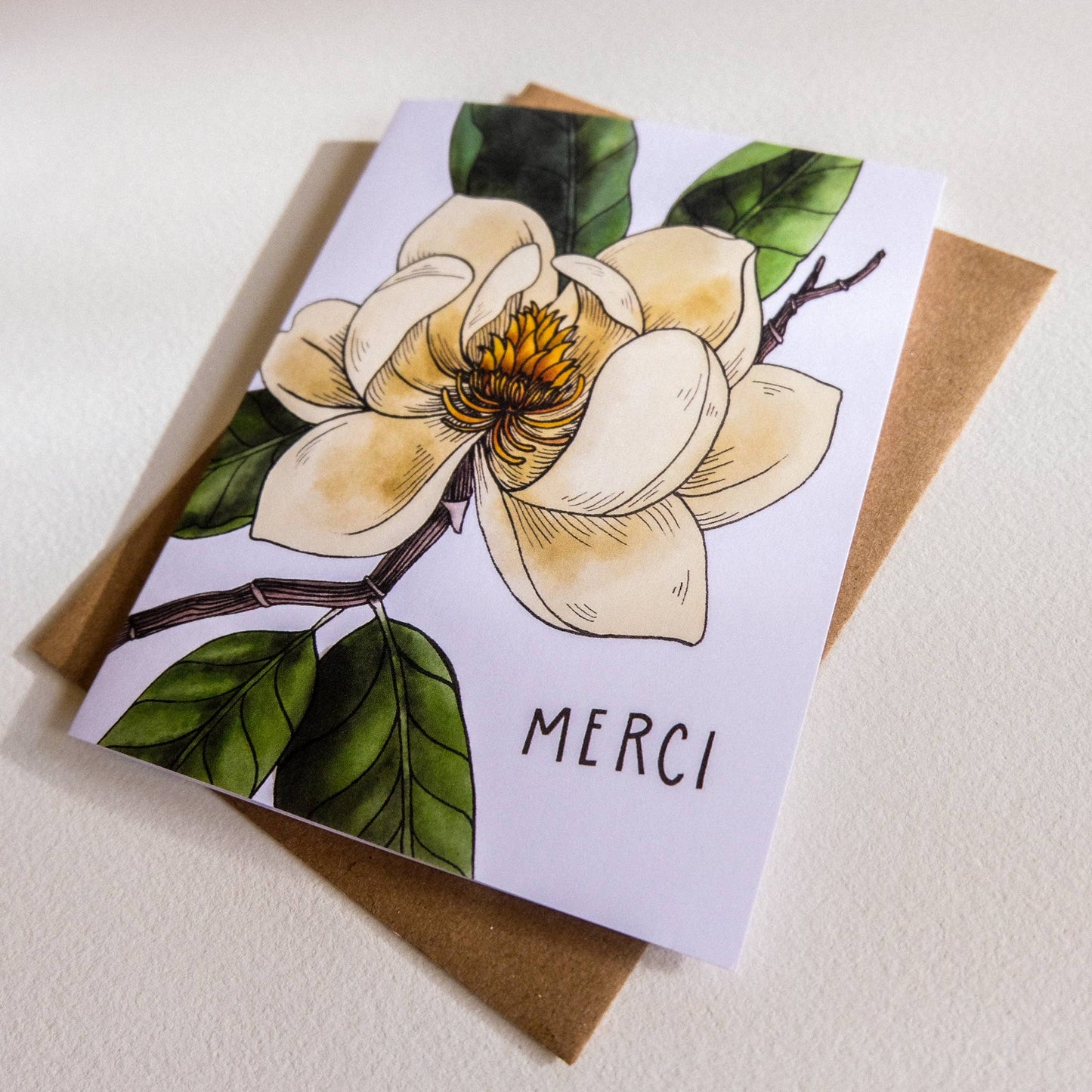 Greeting card with floral design and 'MERCI' text on a white background