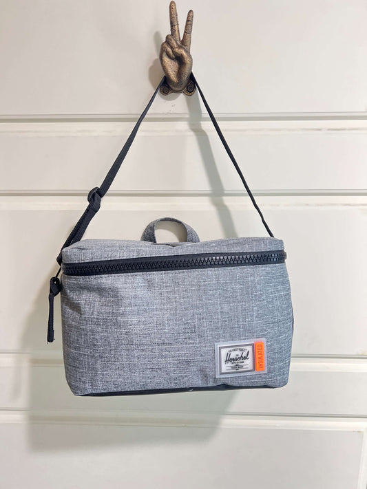 Herschel insulated cooler hanging with a peace sign, featuring a sleek grey design and practical zipper.