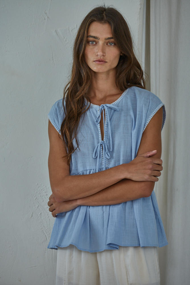 Woman wearing a light blue blouse with a neutral background