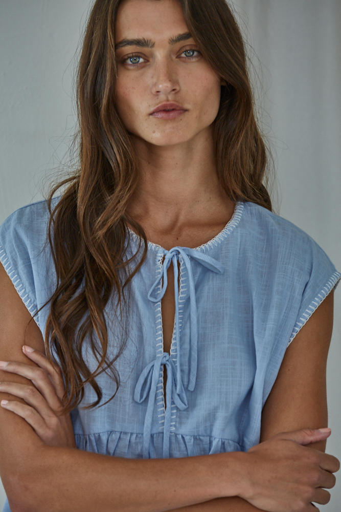 Woman wearing a light blue dress with a plain background
