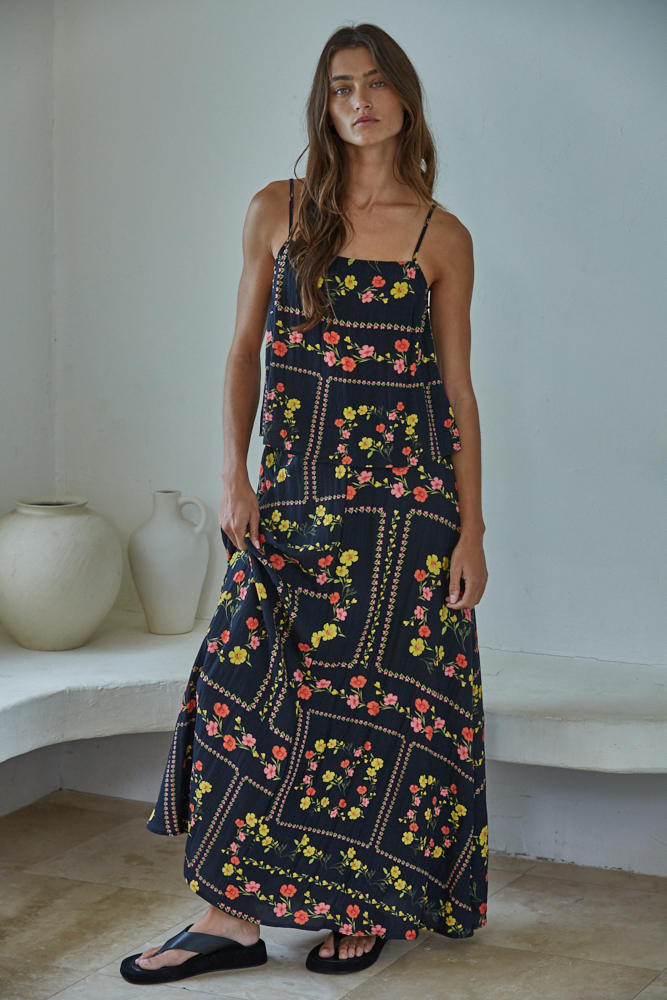 Woman wearing a floral dress standing in a minimalistic room with white walls and a white shelf.