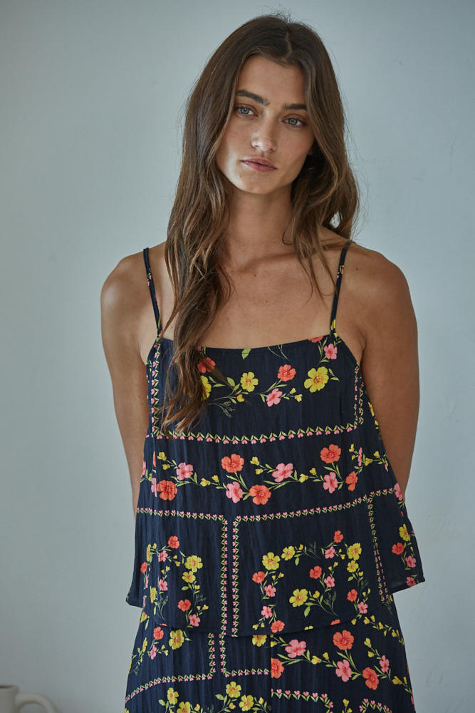 Woman wearing a navy floral dress against a plain background