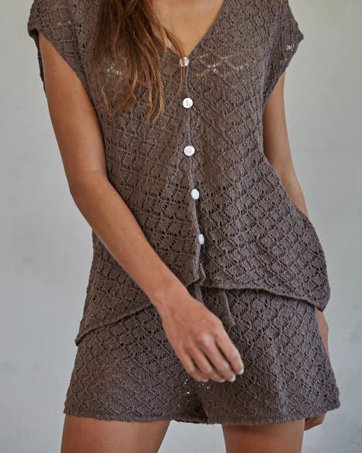 Woman wearing a brown crochet outfit against a plain background