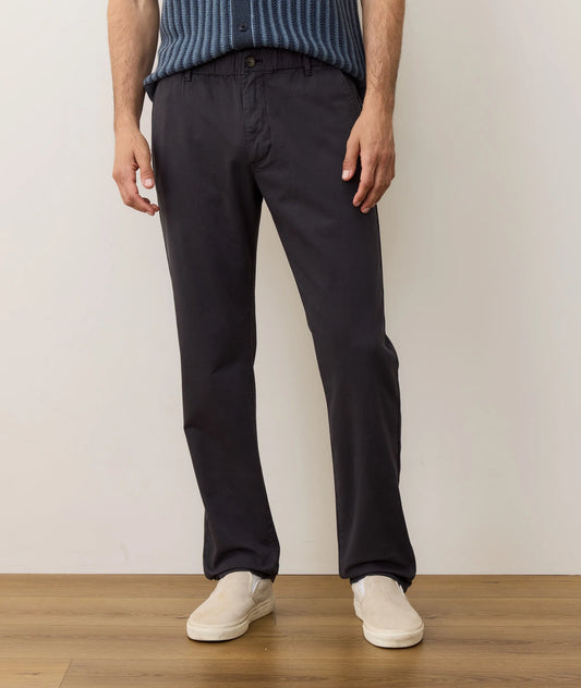 Person wearing black pants and a blue sweater standing against a plain background