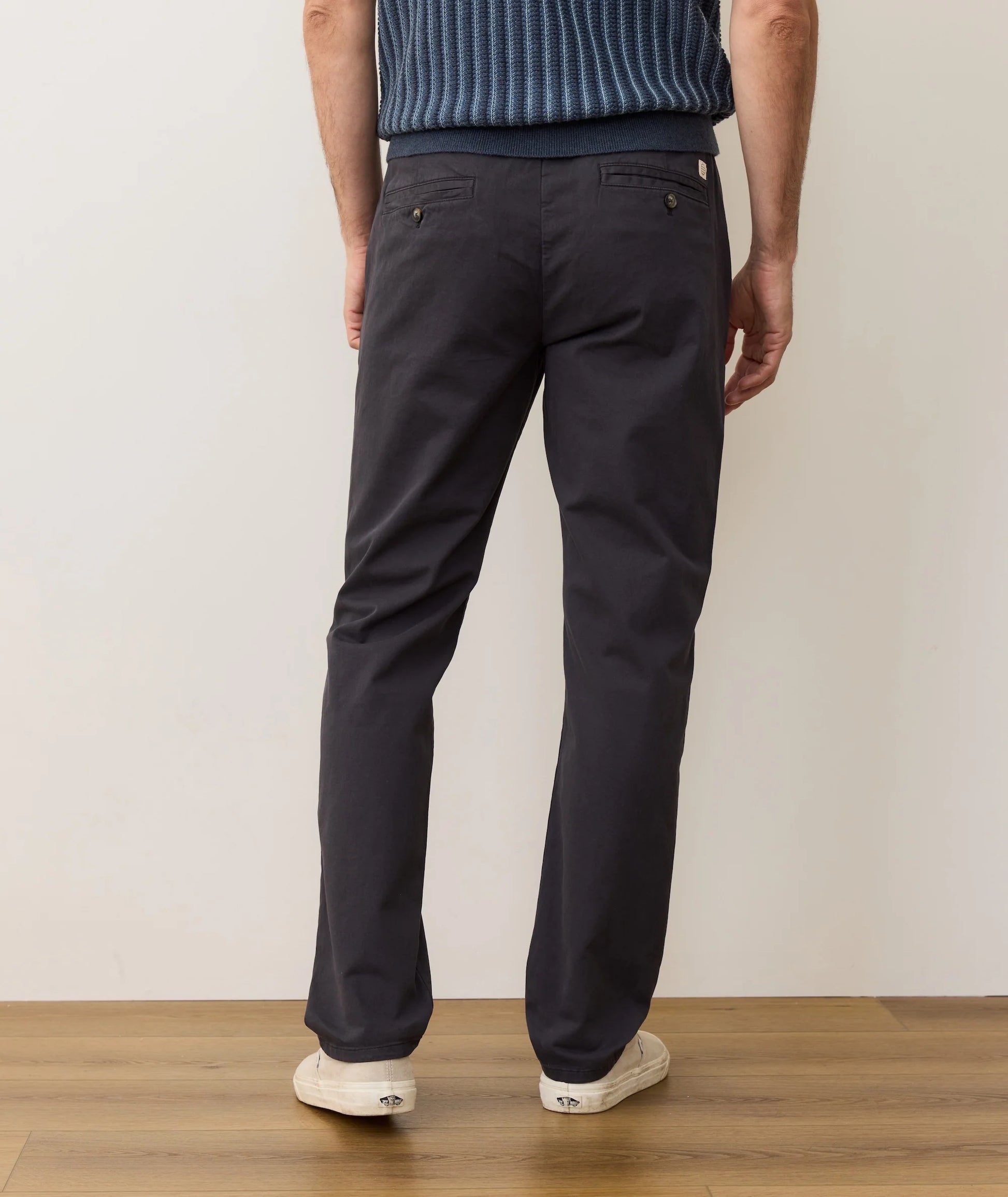 Person wearing navy pants and a blue striped shirt on a plain background